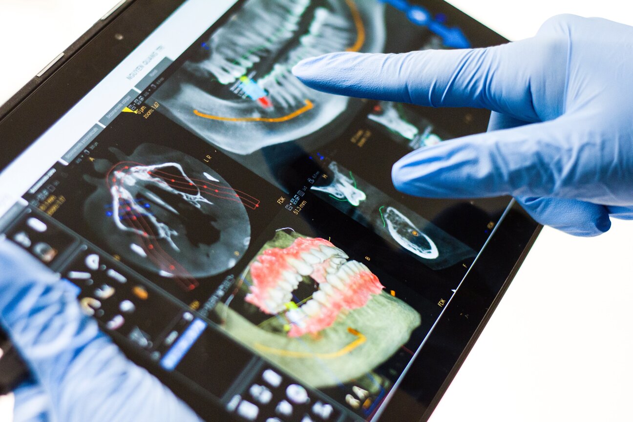 dentist pointing at dental x-rays on digital tablet