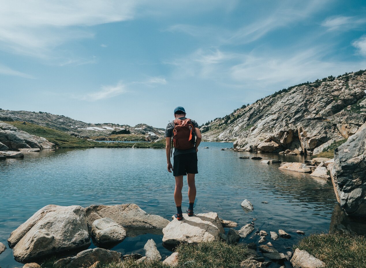 guy standing on rocks overlooking a small pond