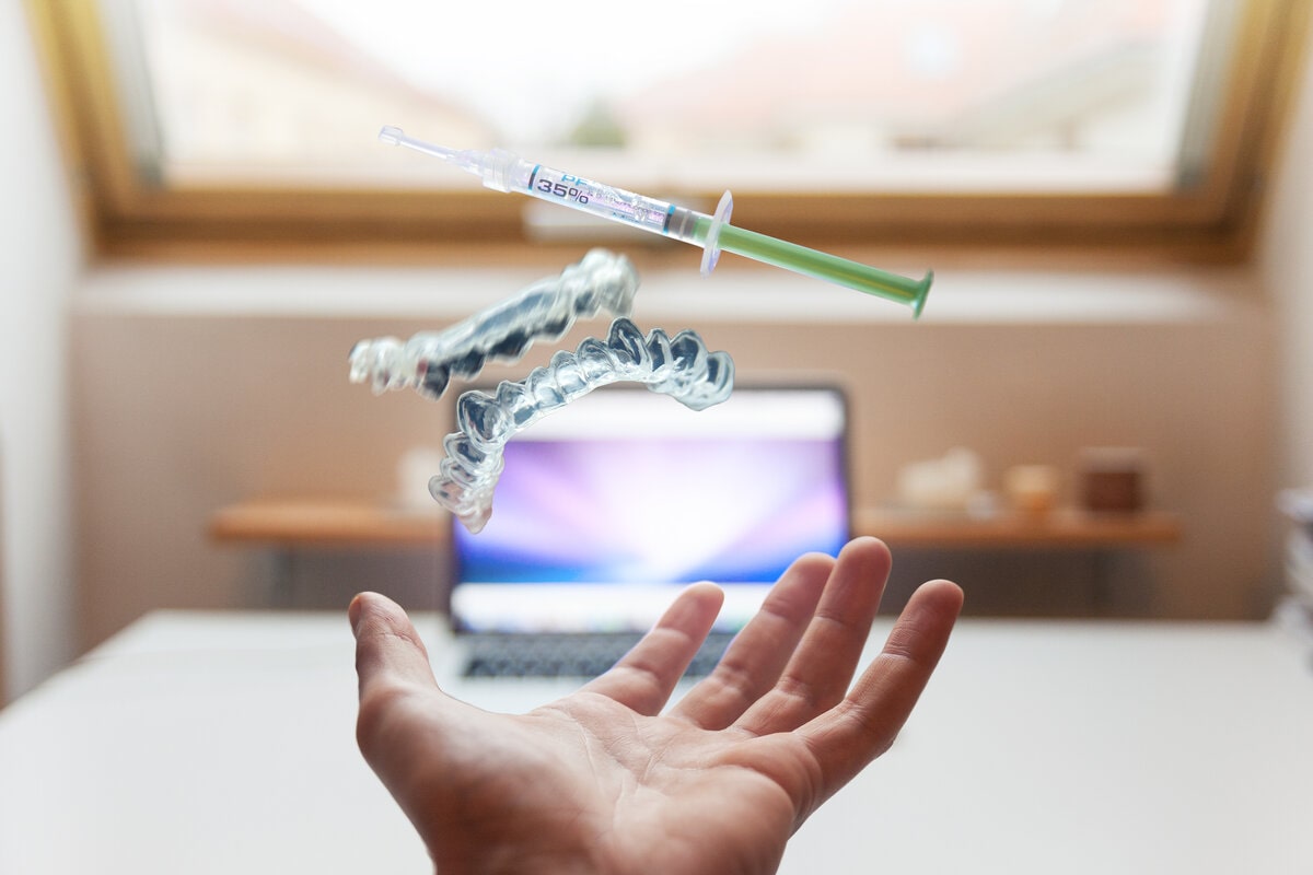 hand under a syringe pair of 3d printed teeth in front of a computer