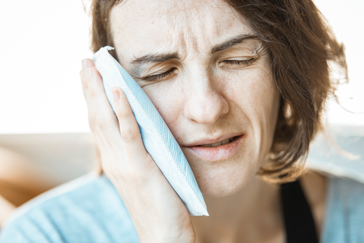 Woman holding a cold compress against her cheek to ease the pain of a toothache