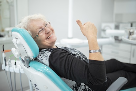 older woman giving thumbs up in dental chair
