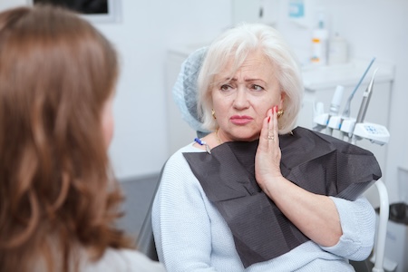older woman with dental pain in exam chair