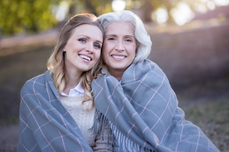 women sharing a blanket and smiling